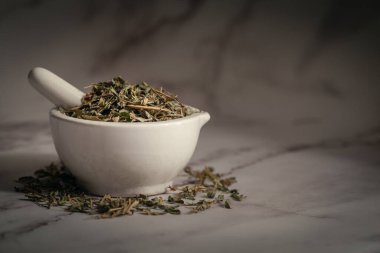 Dry Sharpunkha (Tephrosia purpurea) yaprakları, beyaz seramik havan ve tokmak yakın çekim. Mermer arka planda ön görünüm.