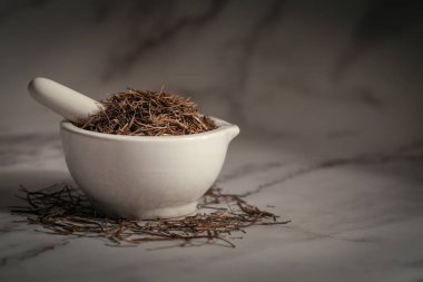 Beyaz seramik havan ve tokmak içinde Kuru Amar Bel (Cuscuta reflexa) köklerine yakın çekim. Marbel arkaplanda ön görünüm.