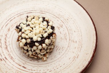 Bir sürü beyaz çikolata parçacıklarıyla süslenmiş lezzetli çikolatalı pastanın yakın çekimi. Beyaz bir tabakta. Üst görünüm.