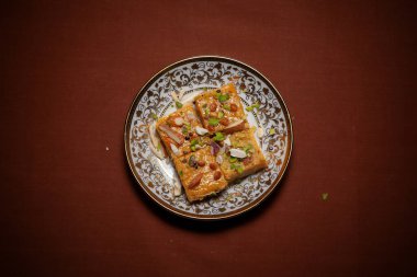 Gram unundan yapılmış ve kuru meyvelerle süslenmiş geleneksel Hint tatlısı Patisha 'nın en üst görüntüsü. Seramik tabakta servis edilir..