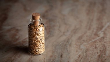 Bir mermer zemin üzerine organik arpa (Hordeum Vulgare) veya jau taneleri ile dolu küçük bir cam şişe yerleştirilir.