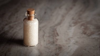 Rafine beyaz şekerle dolu küçük bir cam şişe. Mermer bir arkaplana yerleştirilmiş.