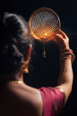 Hintli bir kadın Karwa Chauth festivali sırasında aya süzgeçten bakıyor..