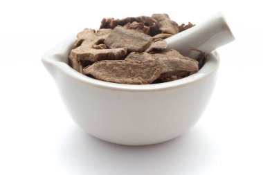 Beyaz bir zemin üzerinde izole edilmiş beyaz seramik havan ve tokmak, kuru organik kapoor kachri (Hedychium spicatum) yakın plan.