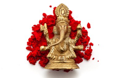 The brass idol of the Hindu God Ganesha is placed over a red-colored sindoor (vermilion) isolated on a white background. Top view clipart