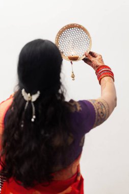 Hintli bir kadın Karwa Chauth festivali sırasında aya süzgeçten bakıyor..