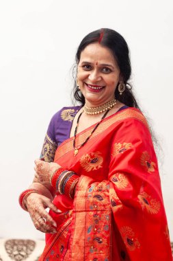 Güzel, mutlu bir Hintli kadın kırmızı bir sari giyiyor ve doğrudan kameraya bakıyor..