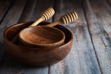 Farklı boyutlarda ahşap kaseler ve ahşap arka planda duran bal damlatıcı..