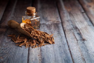 Kuru organik tarçın çubukları (Cinnamomum verum), temel yağıyla birlikte ahşap bir kepçe içinde.