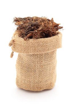 Kuru organik Jatamansi (Nardostachys jatamansi) köklerine yakın çekim, bir jüt torba içinde. Beyaz bir arkaplanda izole edilmiş.