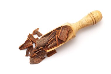 Tahta bir kepçeyle organik tarçın çubuklarının (Tarçın verum) en üst görüntüsü. Beyaz bir arkaplanda izole edilmiş.