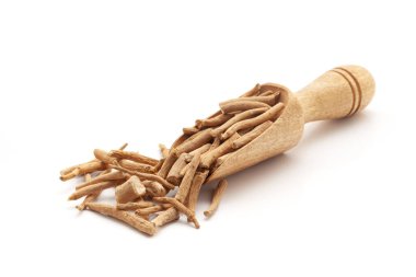 Kuru Organik Ashwagandha (Withania somnifera) kökleriyle dolu ahşap bir kepçenin önü. Beyaz bir arkaplanda izole edilmiş.