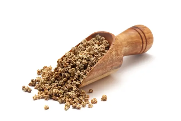 stock image Front view of a wooden scoop filled with dry Organic spinach (Spinacia oleracea) seeds. Isolated on a white background.