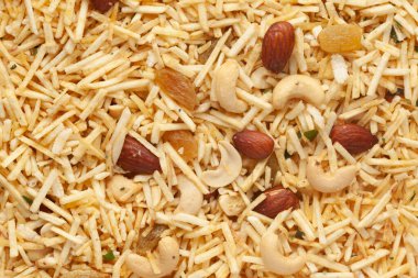 Dilimlenmiş patates, kuru üzüm ve fıstıkla yapılan Aloo Mixture 'ın yakın çekimi. Hint baharatlı çerezleri (Namkeen) tam çerçeve duvar kağıdı. Üst görünüm.