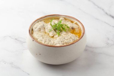 Malai Paneer ya da Kali Mirch ya da Kalimirch 'e yakın plan, üzerine taze yeşil kişniş yaprakları serpiştirilmiş beyaz kremalı (malai) sos ve kara biber tozu serpiştirilmiş. Beyaz granit arka planda seramik bir kasede servis edilir. Seçici odak noktası.