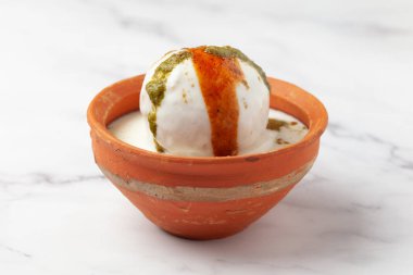 Chaat Dahi vada (AKA Dahi Bhalla, Doi Bora, mosaru vade, Dahi Bara, thayir vadai, perugu vada ). Prepared by soaking vadas in thick dahi (yogurt). Garnished with tamarind chutney sweet and  coriander spicy chutney clipart