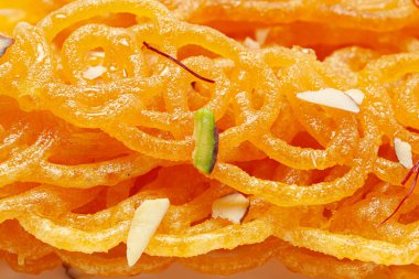 Hint Klasik Tatlı Jalebi 'sinin yakın çekimi. Kesar (Saffron) ve kuru fındıkla süslenmiş Jalebi, Hindistan 'da yaygın olarak kullanılan en lezzetli tatlılardan biridir. Seçici Odaklanma, Konuya Seçici Odaklanma, Arkaplan Bulanık Beyaz .