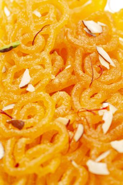 Hint Klasik Tatlı Jalebi 'sinin yakın çekimi. Kesar (Saffron) ve kuru fındıkla süslenmiş Jalebi, Hindistan 'da yaygın olarak kullanılan en lezzetli tatlılardan biridir. Seçici Odaklanma, Konuya Seçici Odaklanma, Arkaplan Bulanık Beyaz .