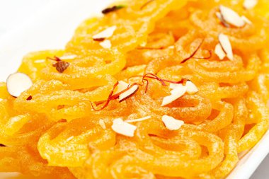 Hint Klasik Tatlı Jalebi 'sinin yakın çekimi. Kesar (Saffron) ve kuru fındıkla süslenmiş Jalebi, Hindistan 'da yaygın olarak kullanılan en lezzetli tatlılardan biridir. Seçici Odaklanma, Konuya Seçici Odaklanma, Arkaplan Bulanık Beyaz .