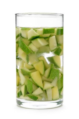 Beyaz arka planda organik yeşil mango dilimleri olan bir bardak votka..