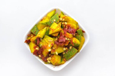 Mangifera indica (Mangifera indica) dilimlenmiş organik Hint mangosu, beyaz kâse içinde zerdeçal, tuz ve kırmızı biber ile tatlandırılmıştır. Beyaz arka planda izole edilmiş. Üst manzara..