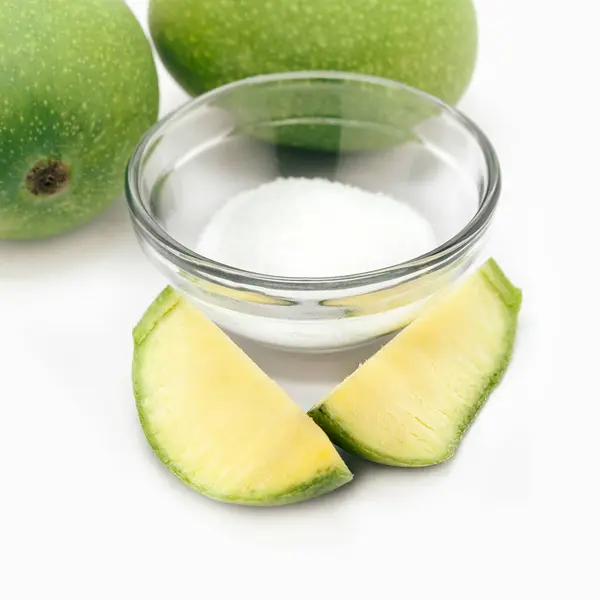 stock image Organic whole and sliced Indian Mango (Mangifera indica), with white salt. Isolated on white background. Front view.