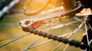 Yakın bir bisiklet tekerleği, detayları ile sabah güneş ışığı altında zinciri ve vites mekanizması.