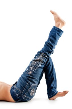 Beyaz arka planda kot pantolon giymiş, yerde yatan bir kızın seksi bacakları.