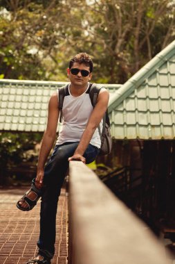 Hint Mutlu genç adam güneş gözlüğü ile evin korkuluk üzerinde oturan