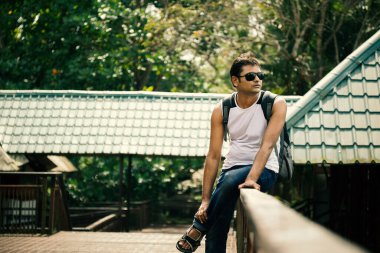 Hint Mutlu genç adam güneş gözlüğü ile evin korkuluk üzerinde oturan