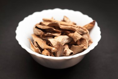 Organik Ekşi kurutulmuş mango veya Aamchur veya Amchoor (Mangifera indica) koyu arka plan üzerinde beyaz seramik kase.