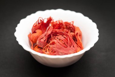 Koyu zemin üzerinde beyaz seramik kase organik Mace veya jayitri (Myristica fragrans).