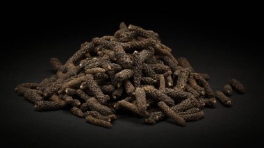 Pile of Organic Long pepper Dried Fruit (Piper longum) on dark background. clipart