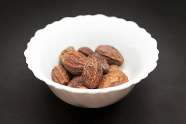 stock image Organic Inknut or Harr (Terminalia chebula) in white ceramic bowl on dark background.