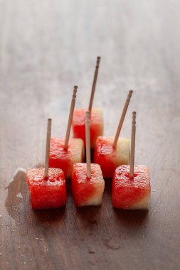 Close-up of Watermelon (Citrullus Lanatus) fruit Cubes with bamboo sticks, on a wooden background. clipart