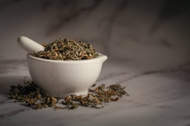 Kuru Organik Marihuana 'nın (Kenevir sativası) beyaz seramik havan ve tokmak ile mermer zemin üzerinde yakın plan.