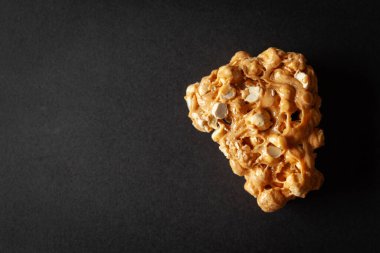 Siyah arka planda bir parça nohut (chana dal) chikki. Tepeden tırnağa. Besin düzlüğü.