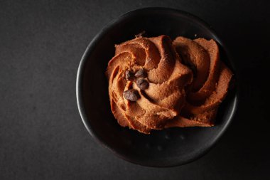 Çikolata parçalı kurabiyeler siyah arka plandaki siyah bir kaseye konur..