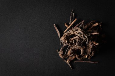 Bir yığın kuru organik Nirgundi (Vitex negundo) kökü, siyah arka planda izole edilmiştir. Üst görünüm