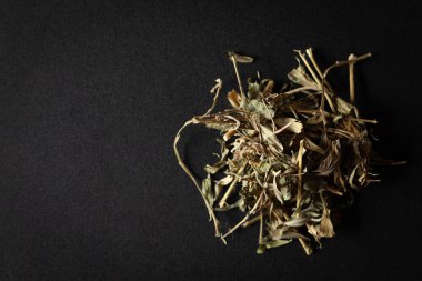 Bir yığın kuru organik Sharpunkha (Tephrosia purpurea) yaprağı, siyah arka planda izole edilmiştir. Üst görünüm