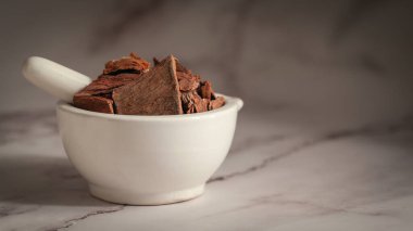 Close-up of Dry Organic Arjuna (Terminalia Arjuna) Barks, in white ceramic mortar and pestle, on a marble background. clipart