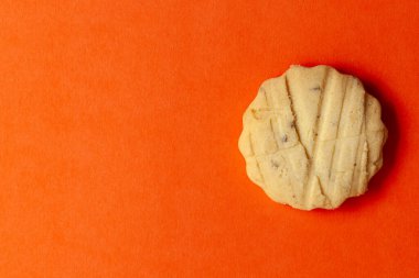 On an orange background, A carrom seeds cookie or salted ajwain cookie. Top-down view. Food Flat lay. clipart