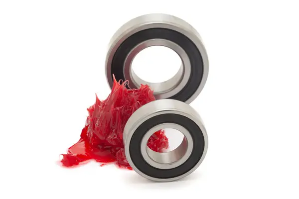 stock image Two tapered roller bearings with red lithium grease (Machinery Lubrication). Isolated on a white background. Front view.