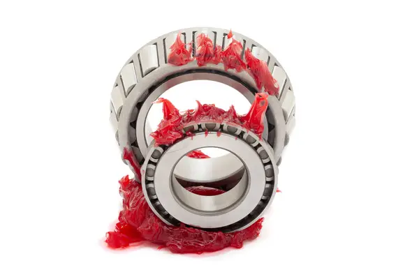 stock image Two tapered roller bearings with red lithium grease (Machinery Lubrication). Isolated on a white background. Front view.