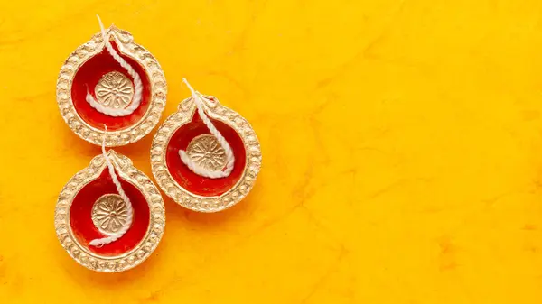 Stock image Top view of red and golden painted decorative Diwali diyas (Earthen oil lamp), on an orange background.