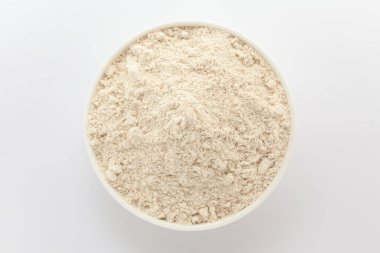 Beyaz seramik bir kasede organik buğday unu (Triticum). Gri bir arka planda izole edilmiş. Üst Görünüm