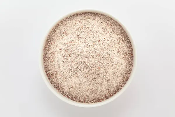 Beyaz bir seramik kasede organik Ragi (Eleusine coracana) veya Parmak Millet unu. Gri bir arka planda izole edilmiş. Üst Görünüm