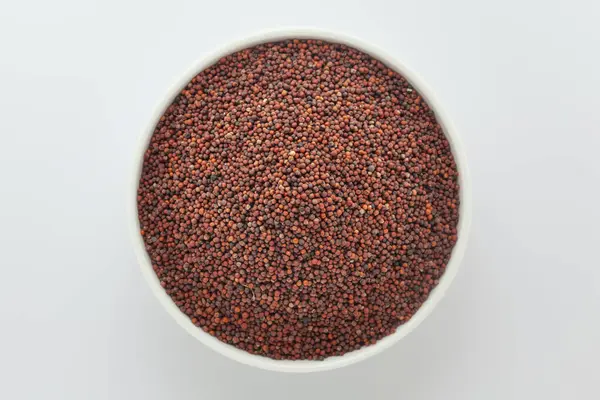 stock image Organic Ragi (Eleusine coracana) or finger millet, in a white ceramic bowl. Isolated on a gray background. Top View