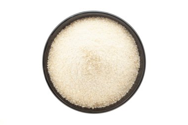 Siyah bir seramik kasede organik pirinç unu (Oryza sativa) bulunur. Beyaz bir arka planda izole edilmiş. Üst Görünüm