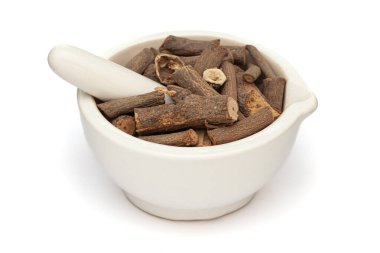 Beyaz bir zemin üzerinde izole edilmiş beyaz seramik havan ve tokmak, kurutulmuş organik Hint saparnası veya Anantmool (Hemismus indicus) yakın plan.